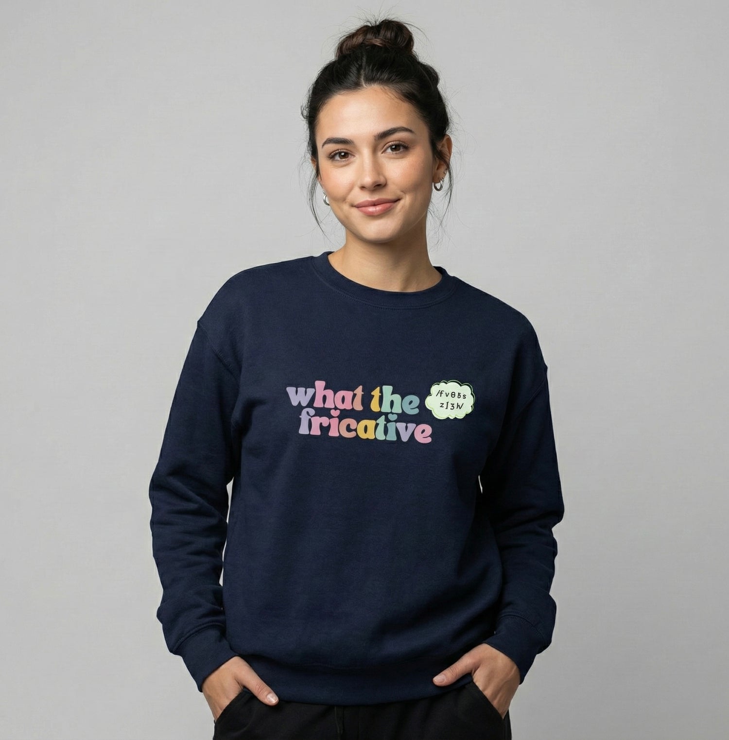 Model wearing a navy “What the Fricative” speech therapy crewneck sweatshirt on a neutral background