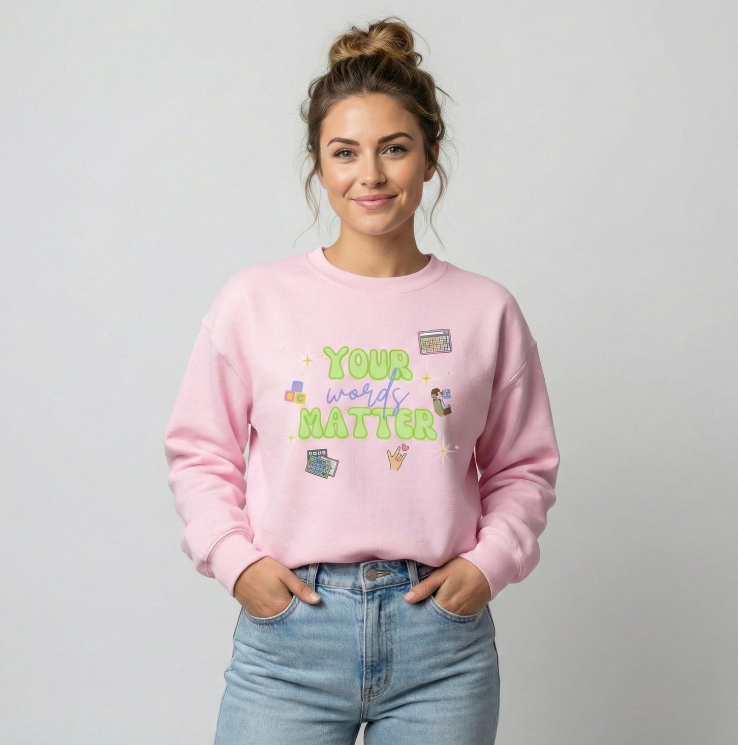 Model wearing a pink “Your Words Matter” speech therapy crewneck sweatshirt on a neutral background